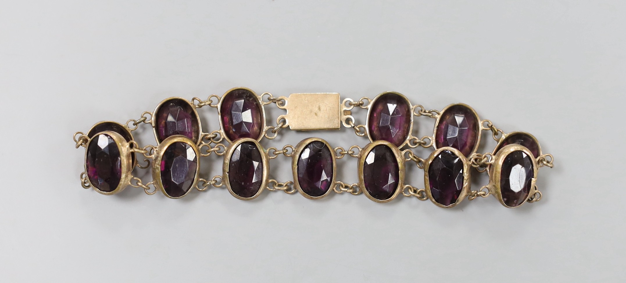 An Edwardian gilt metal and amethyst paste set bracelet, 21cm.